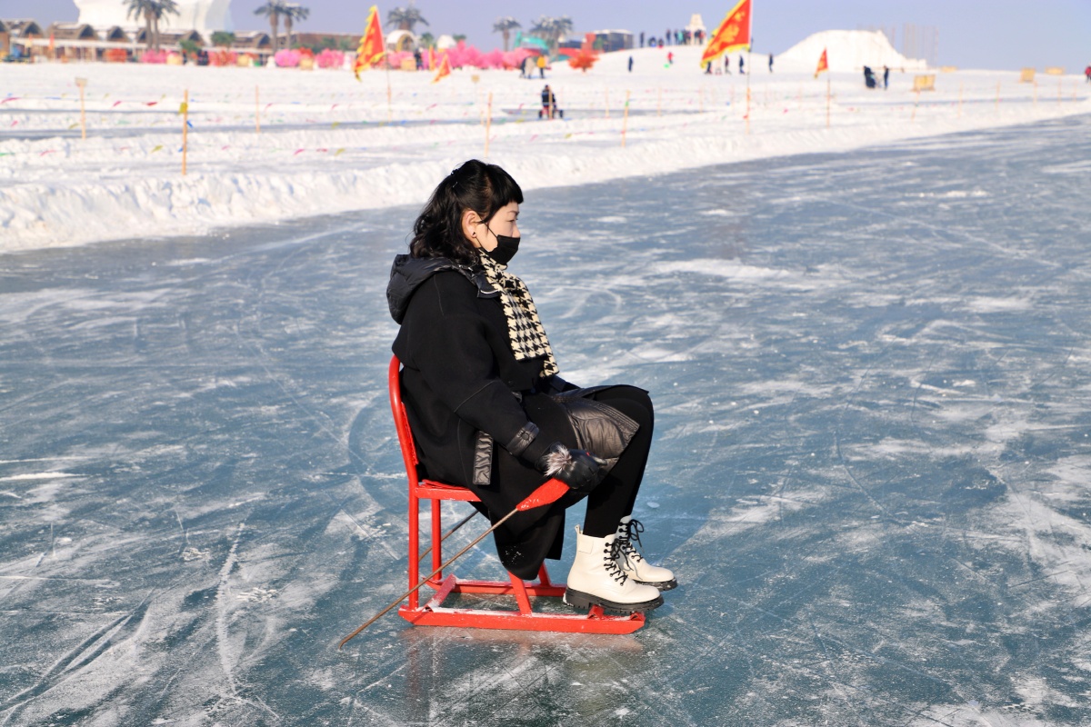 2021年12月25日,新疆博湖县大河口景区,一名游客在玩冰上爬犁.