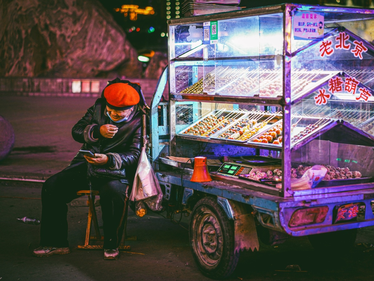 深夜路边摊吃糖葫芦的客人不多对着手机忍不住笑出声的大姐