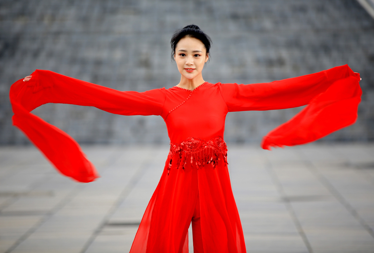 身穿一袭红衣的美女,在广场翩然起舞.