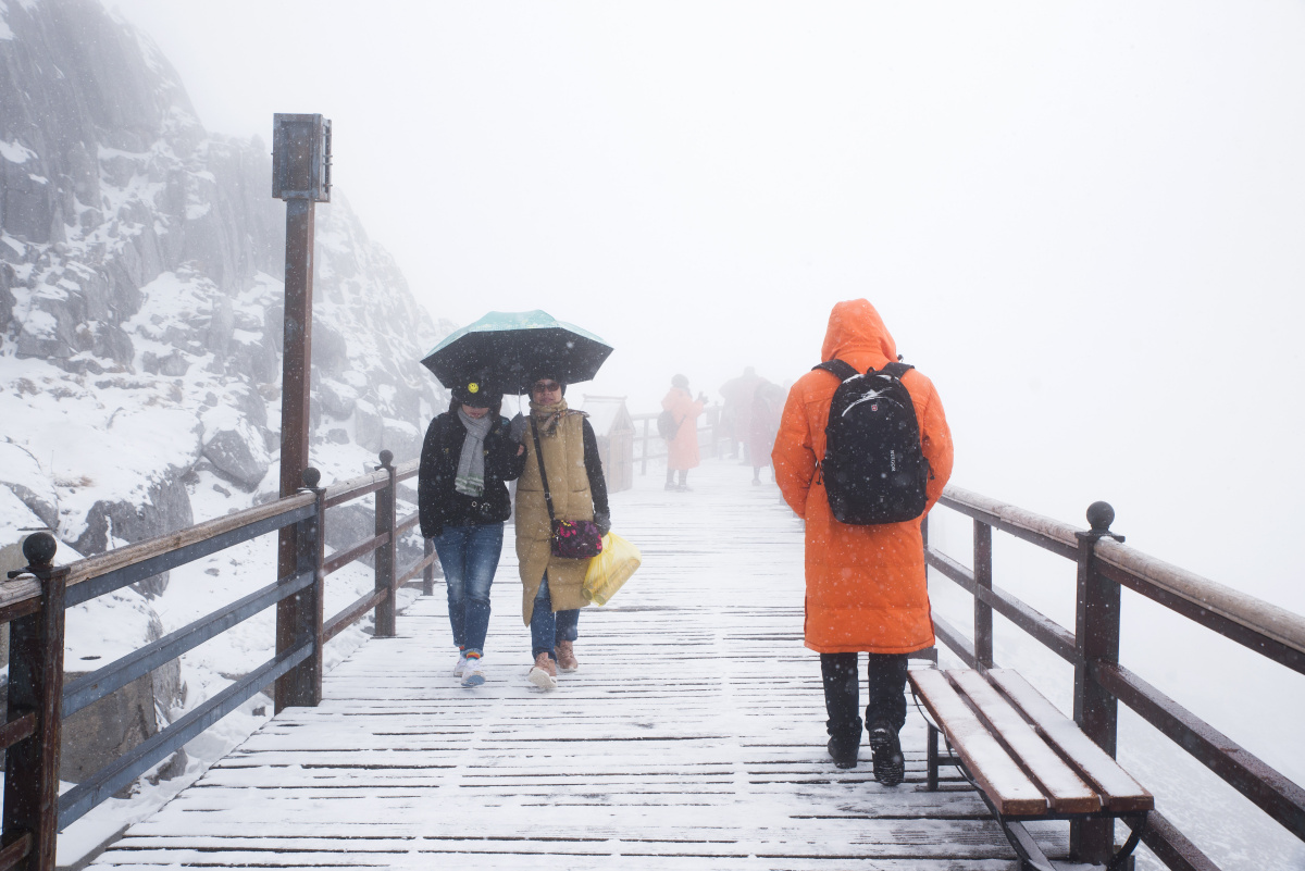 走在寒冷的大雪中,孤独的游客背影和迎面而来的两人形成鲜明