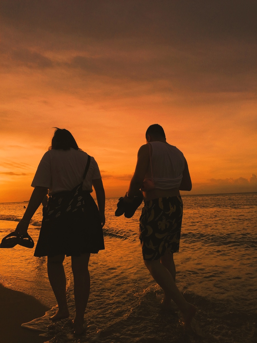 夕阳下在海边拍到了一对情侣正在散步