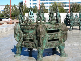 青铜雕塑“火撑子”，蒙古语称做“图拉嘎”，是一种腰缠三箍，上有四个支撑点的火架子。火撑子架在火盆上，里边放干柴。内蒙古呼伦贝尔市海拉尔成吉思汗广场。