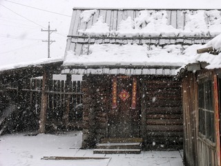 内蒙古额尔古纳市边境村庄太平川，雪中的华俄后裔家庭贴对联的木刻楞房子。
