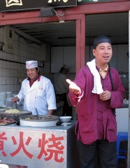 北京王府井小吃街：一家经营“卤煮火烧”小吃店的伙计身穿清朝服装，京腔京韵地叫卖起来，颇有老北京遗风（摄于2004年11月）