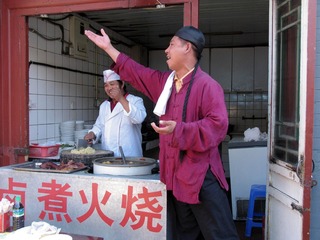 北京王府井小吃街：一家经营“卤煮火烧”小吃店的伙计身穿清朝服装，京腔京韵地叫卖起来（摄于2004年11月）
