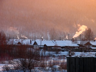 内蒙古呼伦贝尔北部，冬季的村庄雪景，山林人家炊烟袅袅。