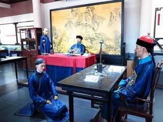 率性堂场景，率性堂是国子监的高级班，有助教和学正两位老师。学生恭敬站在老师身侧，向老师请教问题。如果学生对老师的讲授有质疑，为表示尊敬，学生则要跪在老师面前提出疑问。北京孔庙和国子监博物馆。