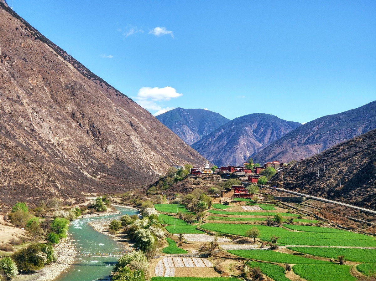 积雪融化小溪流动蓝天白云下的绿水青山拍于四川省巴塘县