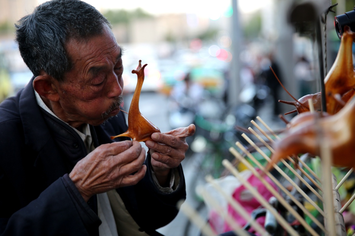 吹糖人这种传统手工艺在城市几乎看不到了老人全神贯注地吹糖人成了
