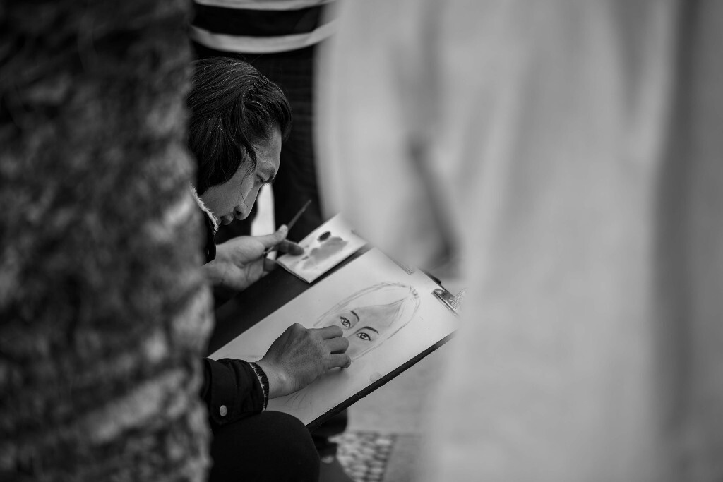 公园里，街头画师正在给一位美女绘制肖像，他专注的眼神让我忍不住按下快门。