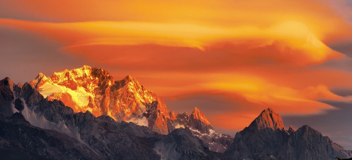 丽江清晨,云团聚于玉龙雪山之上,日出东方,雪山红云浸染