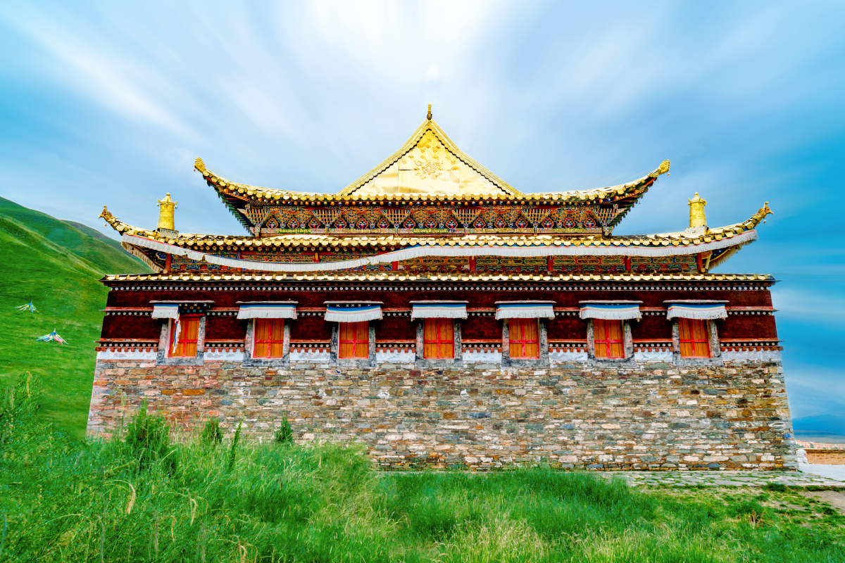 山谷中的金顶寺庙祁连山满山青草的山间一座金顶的藏族寺庙屹立其间