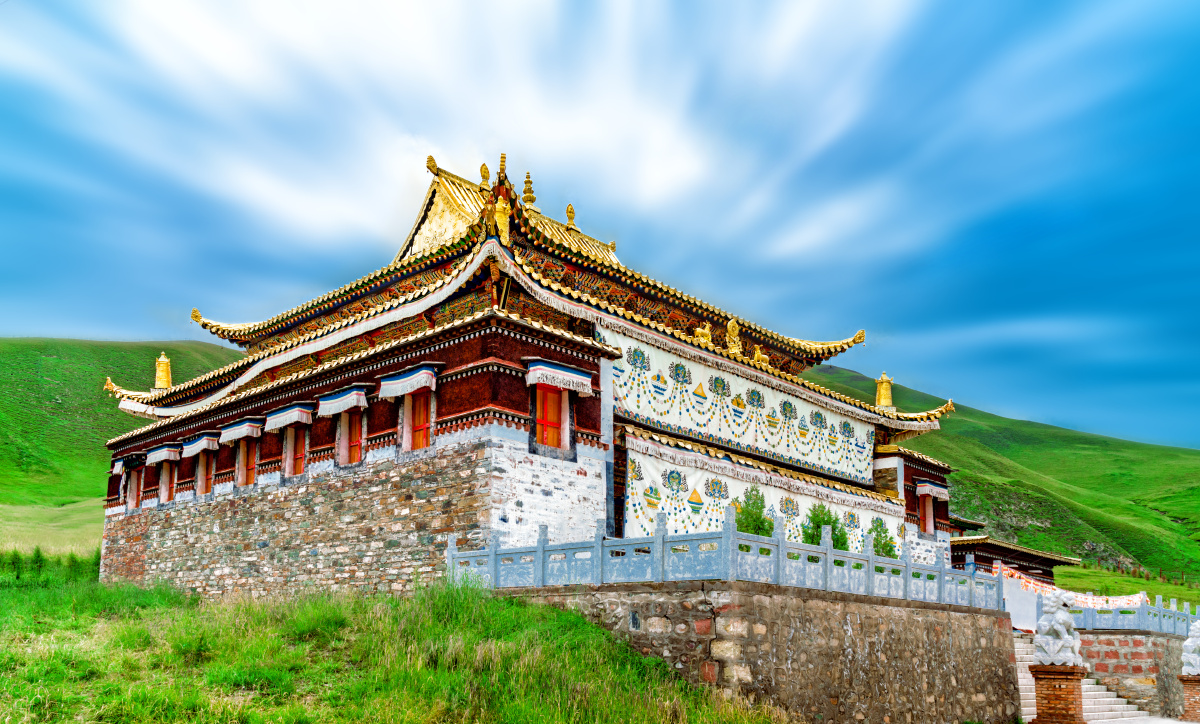 山谷中的金顶寺庙祁连山满山青草的山间一座金顶的藏族寺庙屹立其间