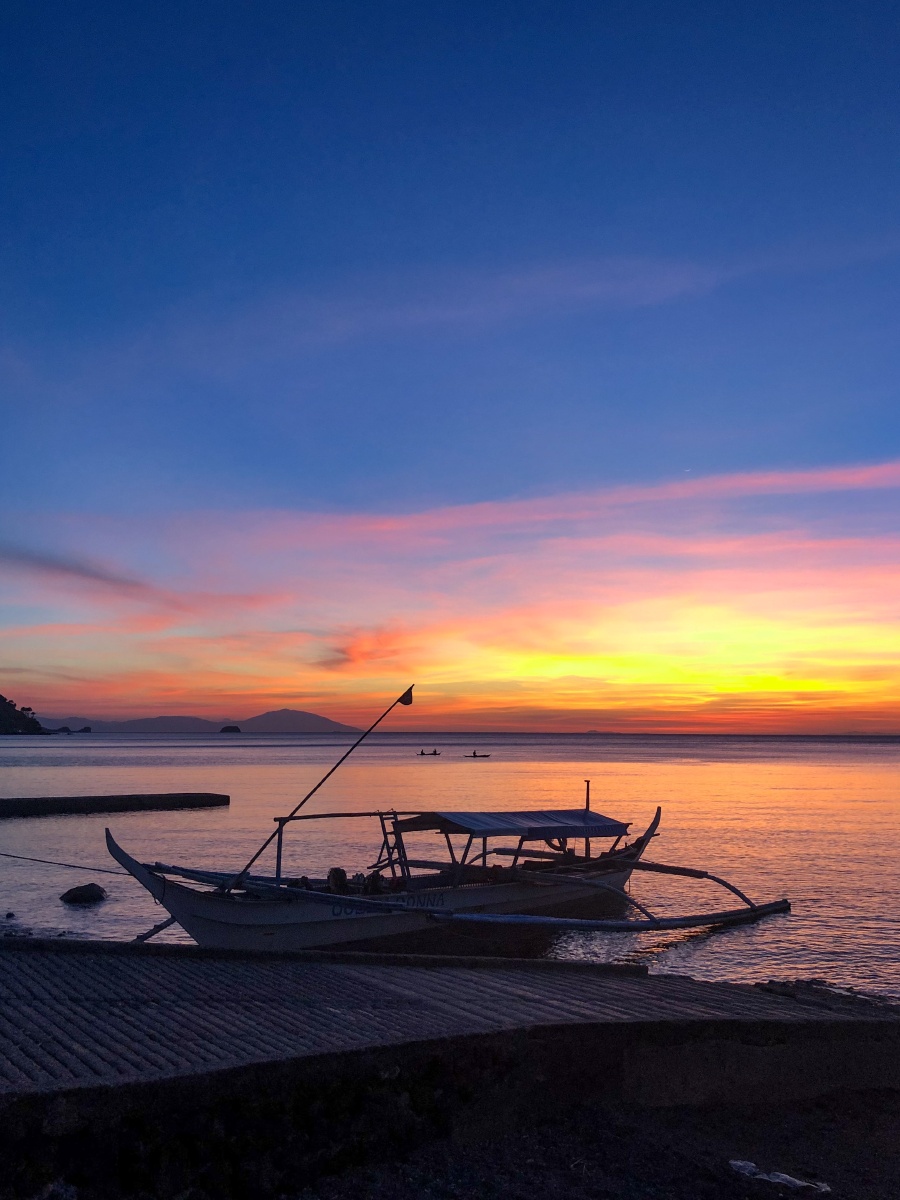 夏日的海边晚霞中归岸的小船