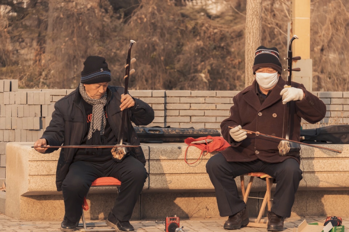 冬日暖阳和蔼的老人家相约在公园一同拉奏二胡其乐融融