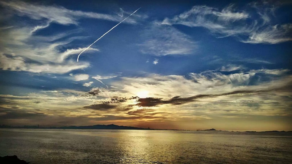 飞机划过天空，与夕阳融为一体，抓拍下这一瞬间