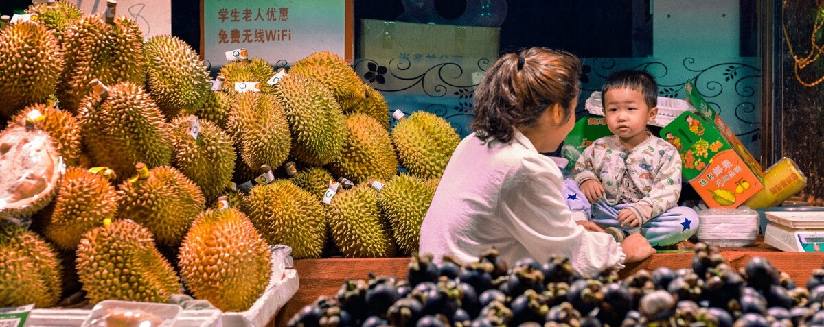 卖木菠萝和山竹的店主面前有几个小混混在大声说着什么，我在旁边看了5分钟，什么也没买只顾着问老板有没有结婚有没有男朋友。我走过去拍摄，大概人面对镜头总容易不自然，很快就走了。对了，这个小朋友是老板的侄女好像。