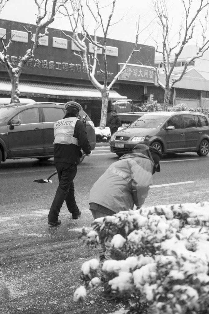 警察叔叔与环卫叔叔在铲除路面积雪，辛苦了！