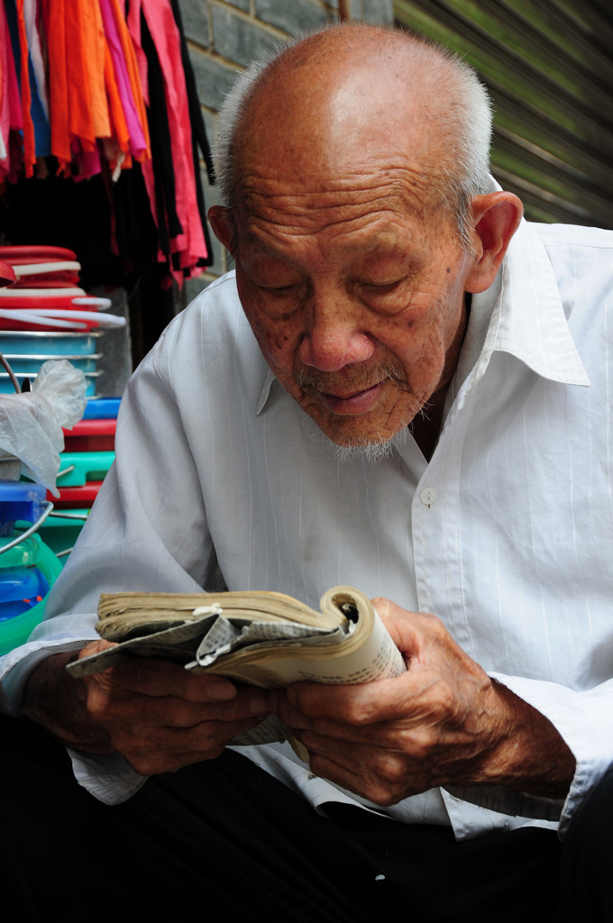 清晨,老街早起的长者,在捧着一本书页卷边的破旧书籍,津津有味