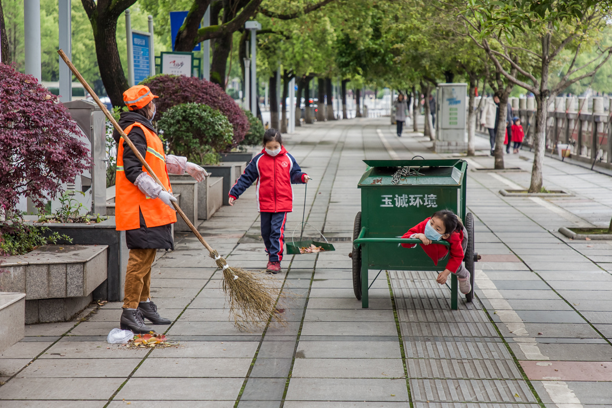 2020年4月1日,湖南浏阳,一位环卫工带着两个尚未开学的孙女在清扫人行