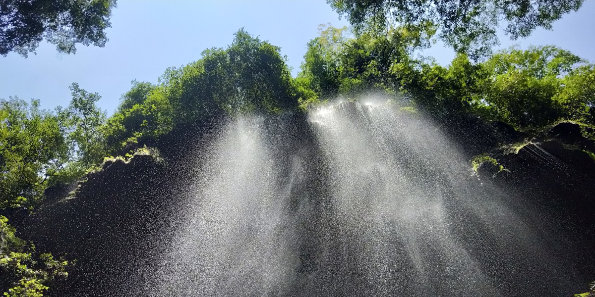 刚开始的雨季峡谷里到处弥漫着水汽望着崖壁上的水瀑沐浴在阳光之下