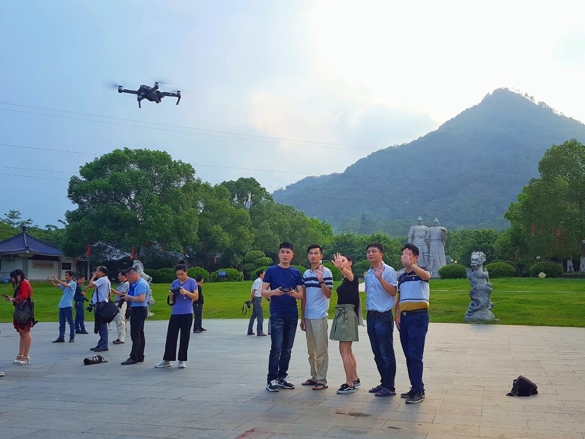 看到几个人在公园里使用无人机合影,享受现代生活的便捷,用