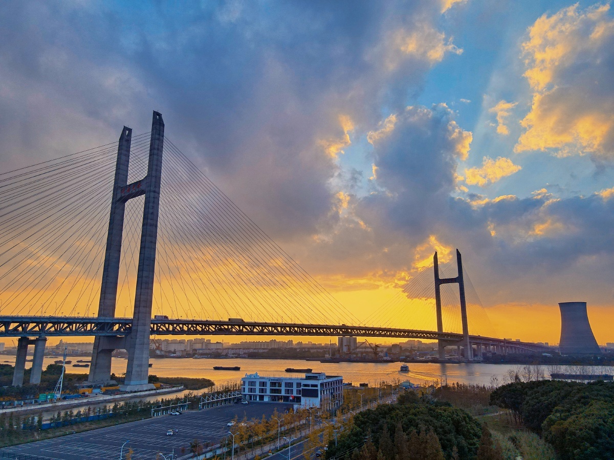 傍晚航拍上海浦东闵浦大桥,霞光透过云层洒在江面上.暖意的画面!
