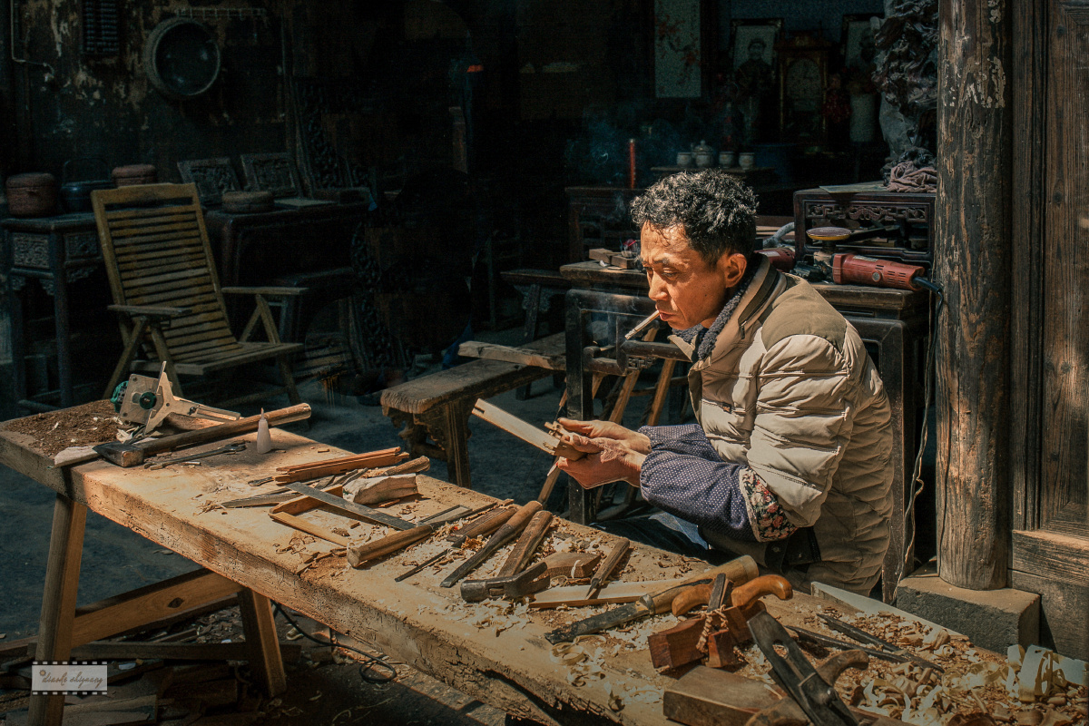 江西婺源行摄,街巷里,一位雕刻师正在聚精会神地工作,瞬间拍