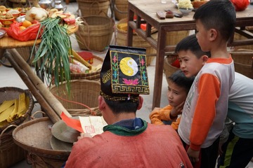 24相对于拜神求福，充满好奇心的小朋友对神秘的传统仪式抱有更浓厚的兴趣，饶有兴致地围在主道身边聆听念咒。