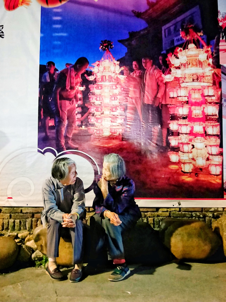二位大妈坐在宣传画前说着悄悄话