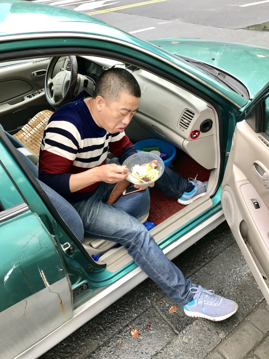 4月7日,在杭州古荡公交终点站,这位的士司机就在马路边上解决午饭