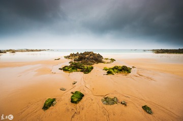 Empty beach with rocks and dark sky