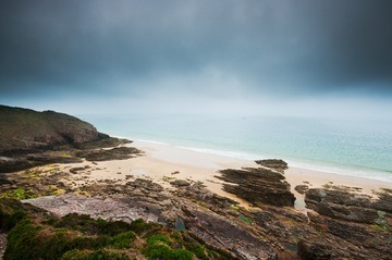Beach with rocks and cloudy dark sky