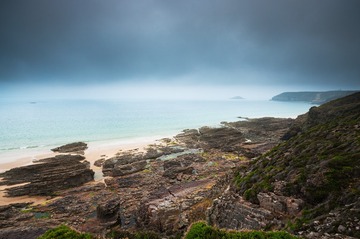 Rocks and beach with a dark cloudy sky