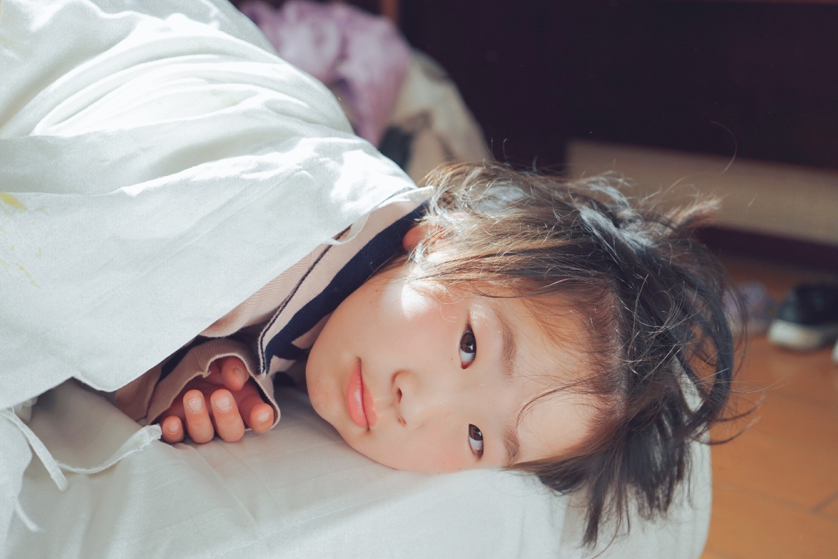 懒床小姑娘早上太阳光从窗外照进来小姑娘一脸倦意赖在床上不愿起来