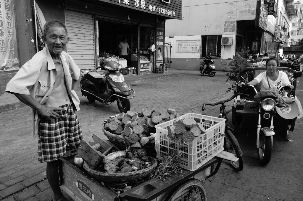 60多岁的龚大爷清晨从十几公里外的郝堂村过来,将今天采摘的新鲜莲子带到市场。2017年7月25日摄于信阳市体彩广场附近。