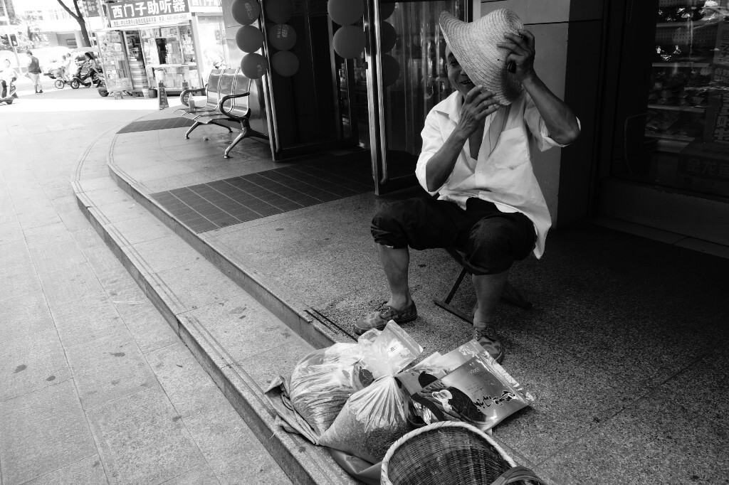 张大爷进城卖鸡蛋和茶叶,由于不在菜市场,他见到我拍照,赶紧用草帽遮住脸,不停地说,别拍别拍,我一会就走。2017年7月25日摄于信阳市中山路。