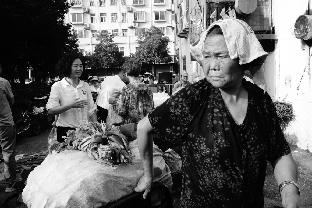 今天真热,任大妈头顶毛巾不搭理我,她已经习惯我天天拍照,拉着装满菜的车子在市场上行走。2017年7月26日摄于信阳市京杯农贸市场。