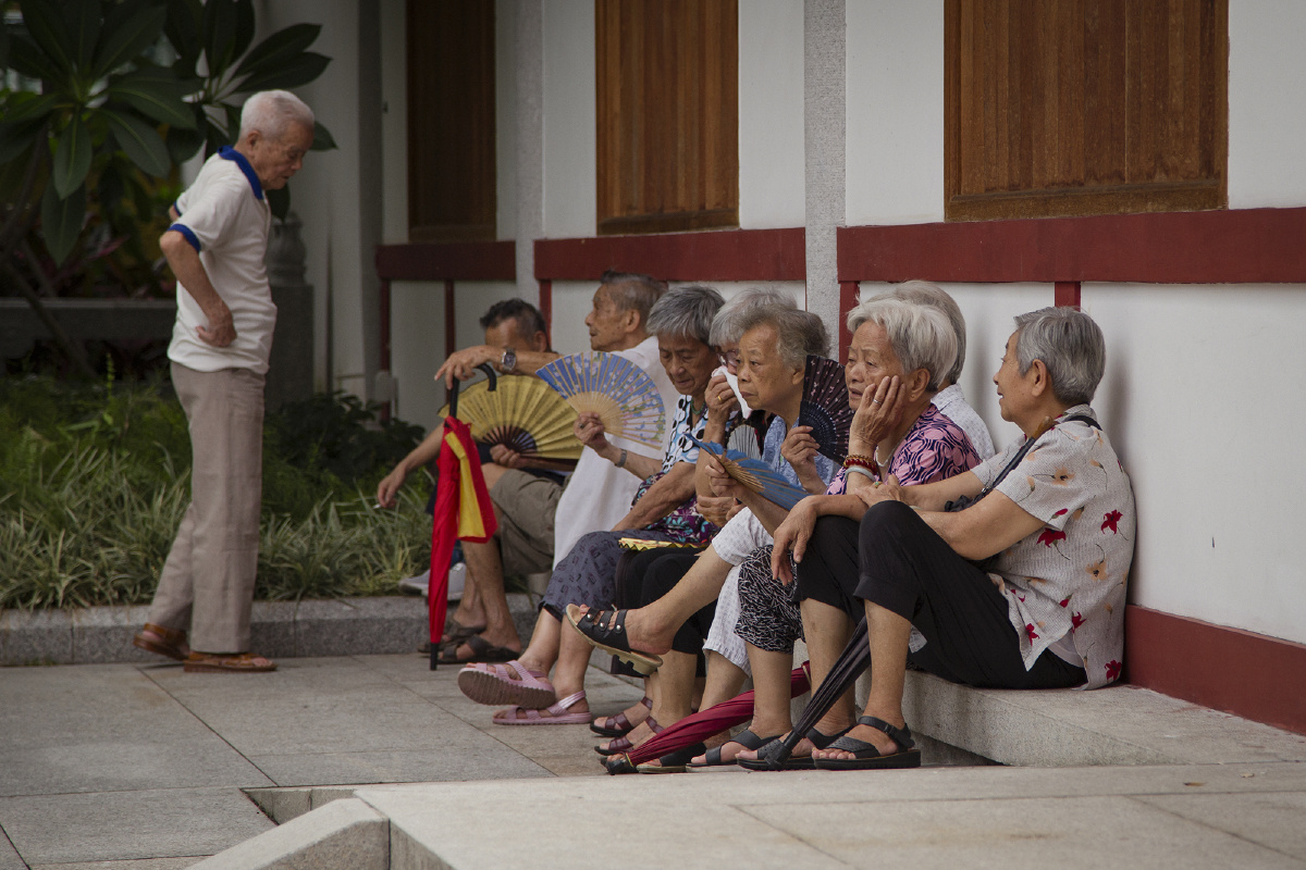 一群在寺庙里刚上完香的老年信众坐在光孝寺门口外的石阶上