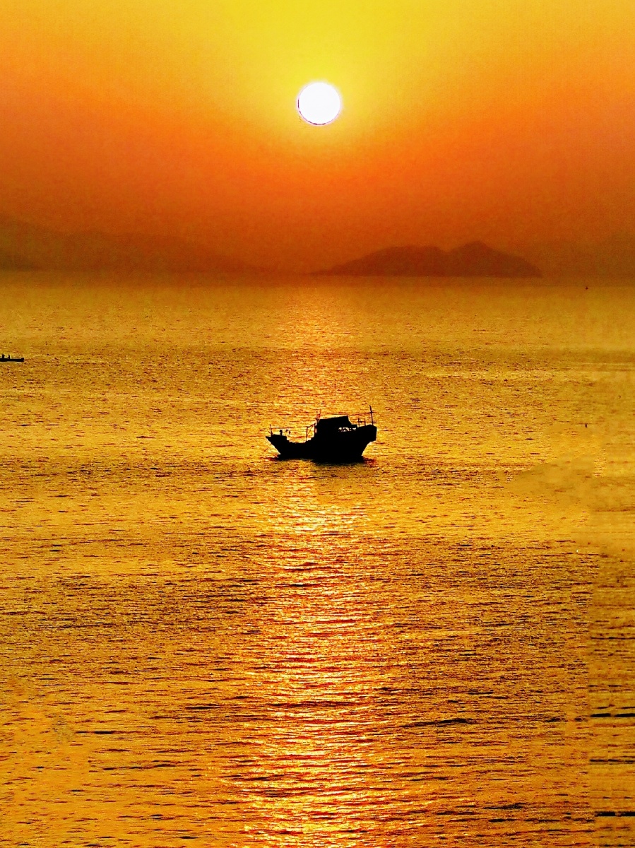 渔舟荡漾夕阳映照万顷碧波海上缓缓而行的帆影