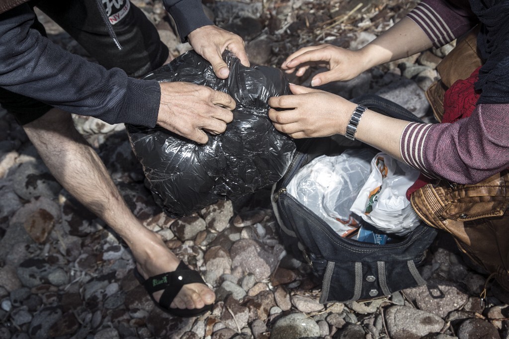 2015年10月19日，希腊莱斯沃斯岛，亚扎和妻子在检查携带的物品是否漏水。