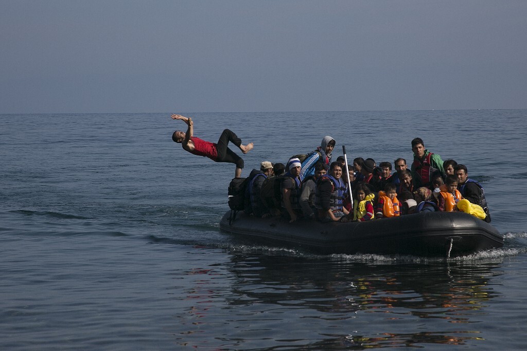 2015年10月19日，希腊莱斯沃斯岛，来自阿富汗的亚扎从皮划艇跳进爱琴海。