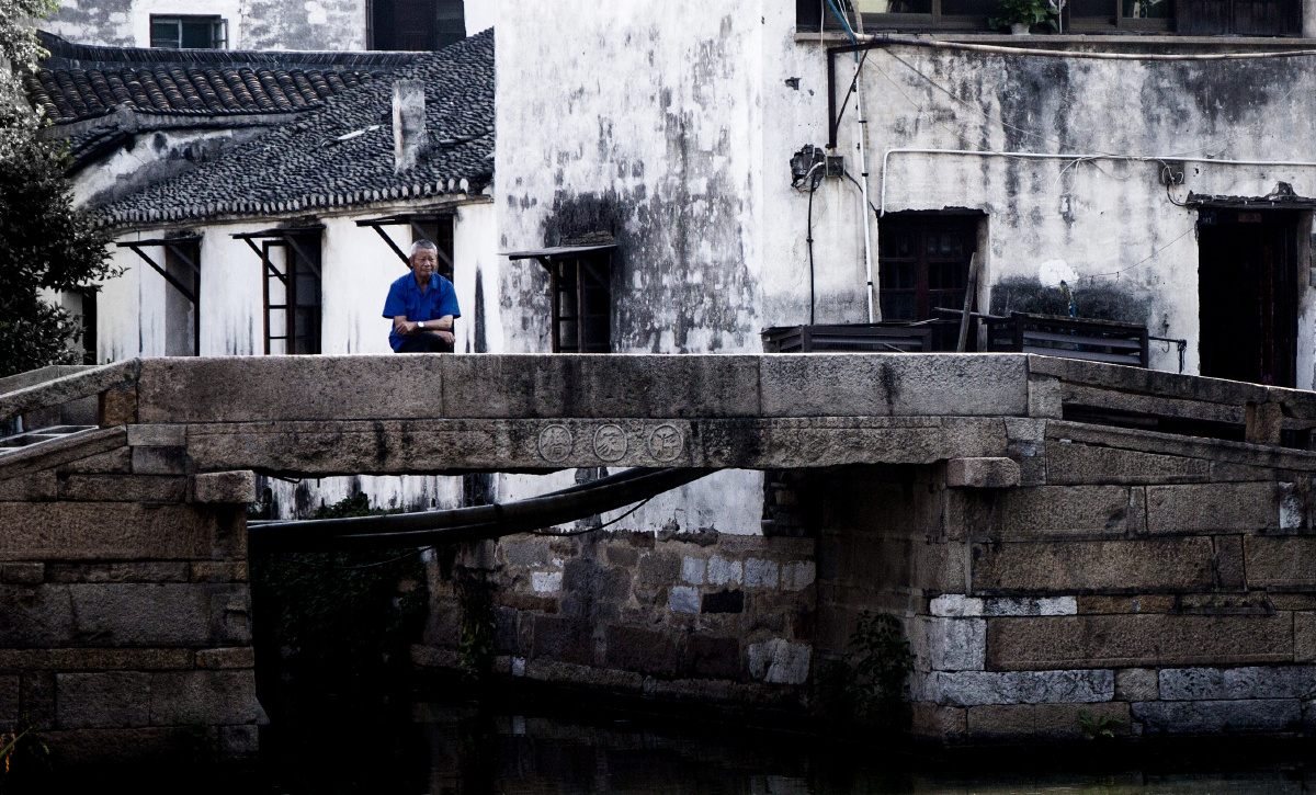 一位老人独自坐在同里古镇蒋家桥上