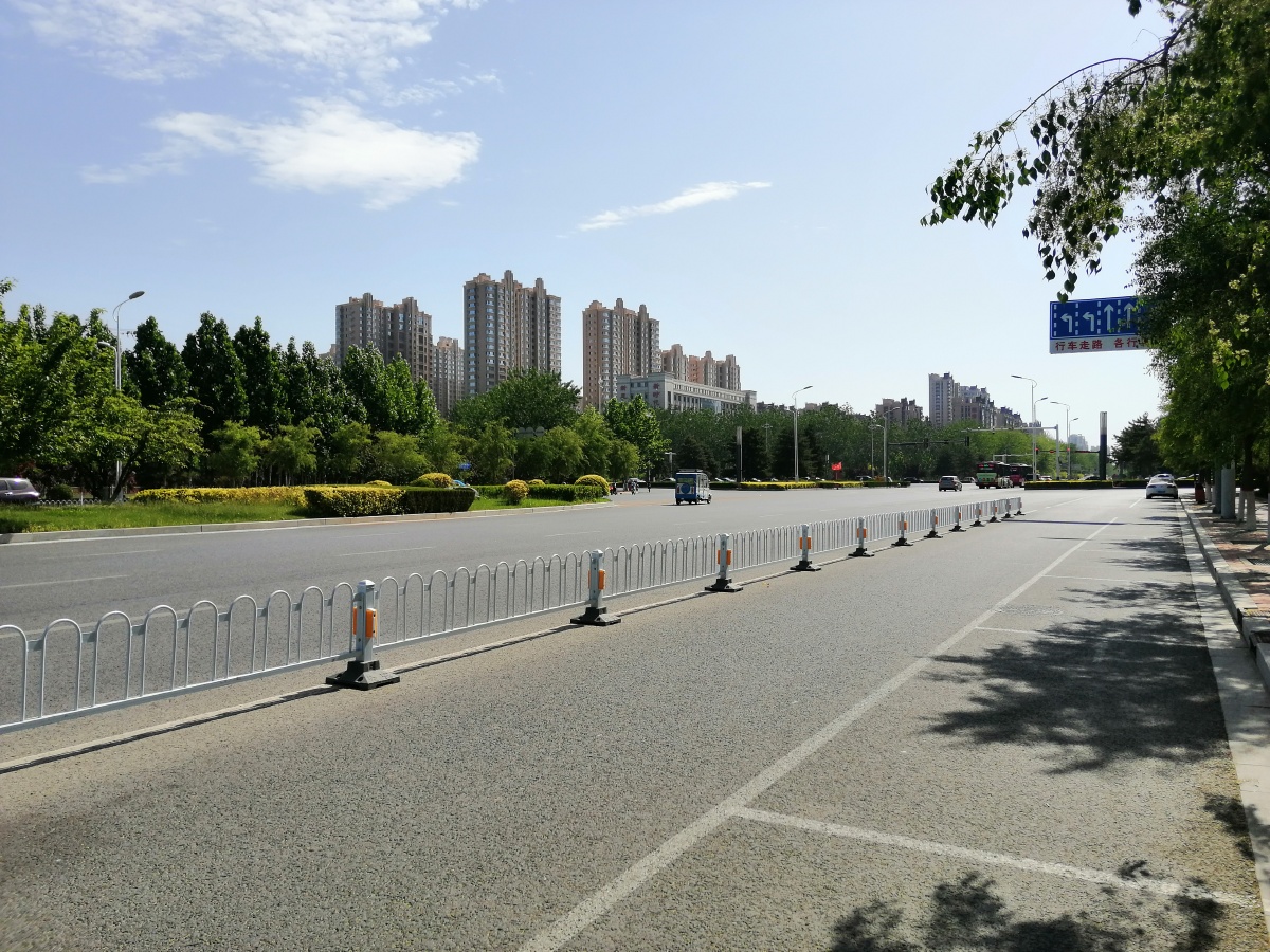 夏日里北方城市沧州的街道有骑电动车的行人和三轮车