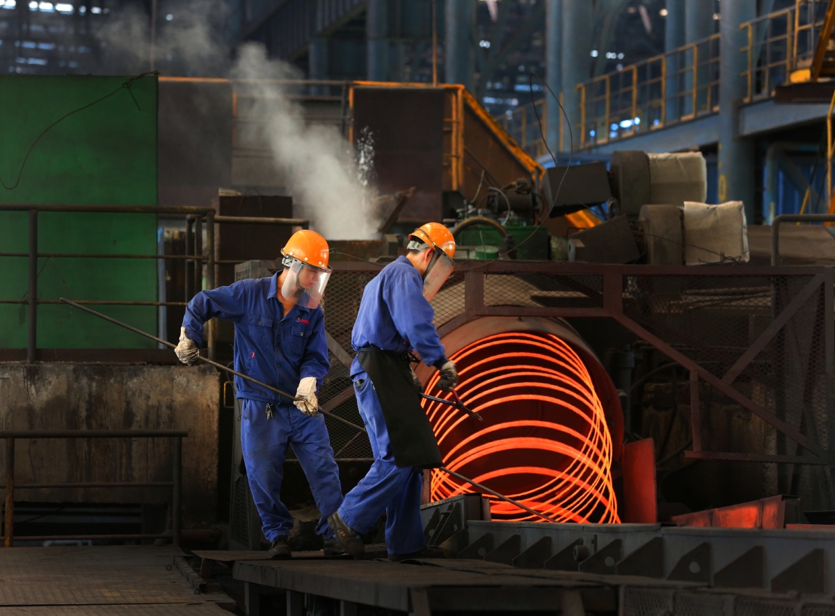 两个出钢工人小心把热钢钳放在钢槽上,周边的温度很高烧钢的