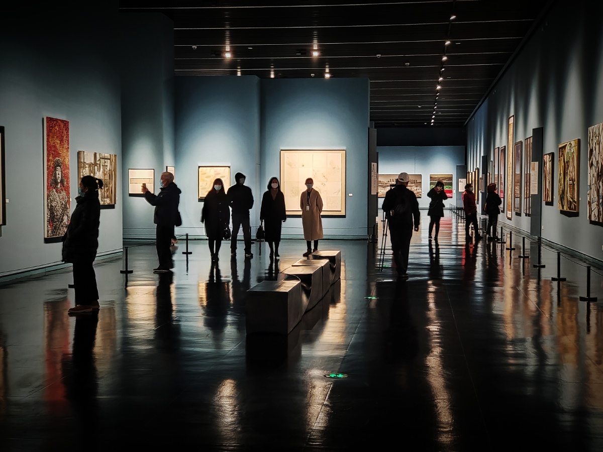 在静谧之中的聚光灯下看画展的形形色色的人