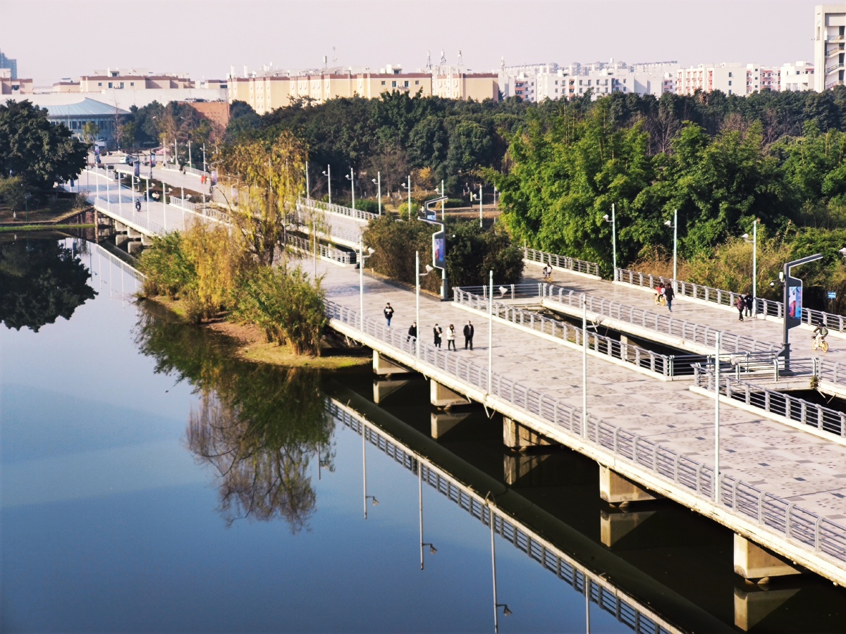 四川大学江安校区第一教学楼前的小木桥和明远湖上的长桥显得宁静而