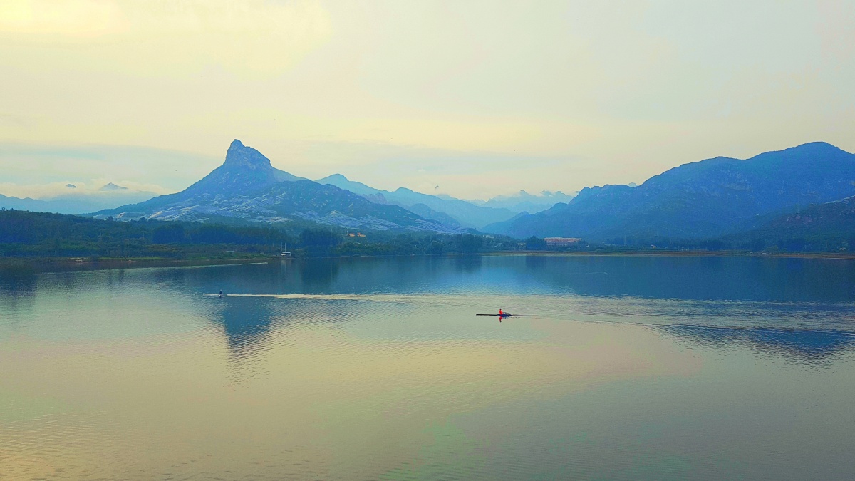 暮色中远山如黛一叶小舟荡漾在波光粼粼的平静的湖面上