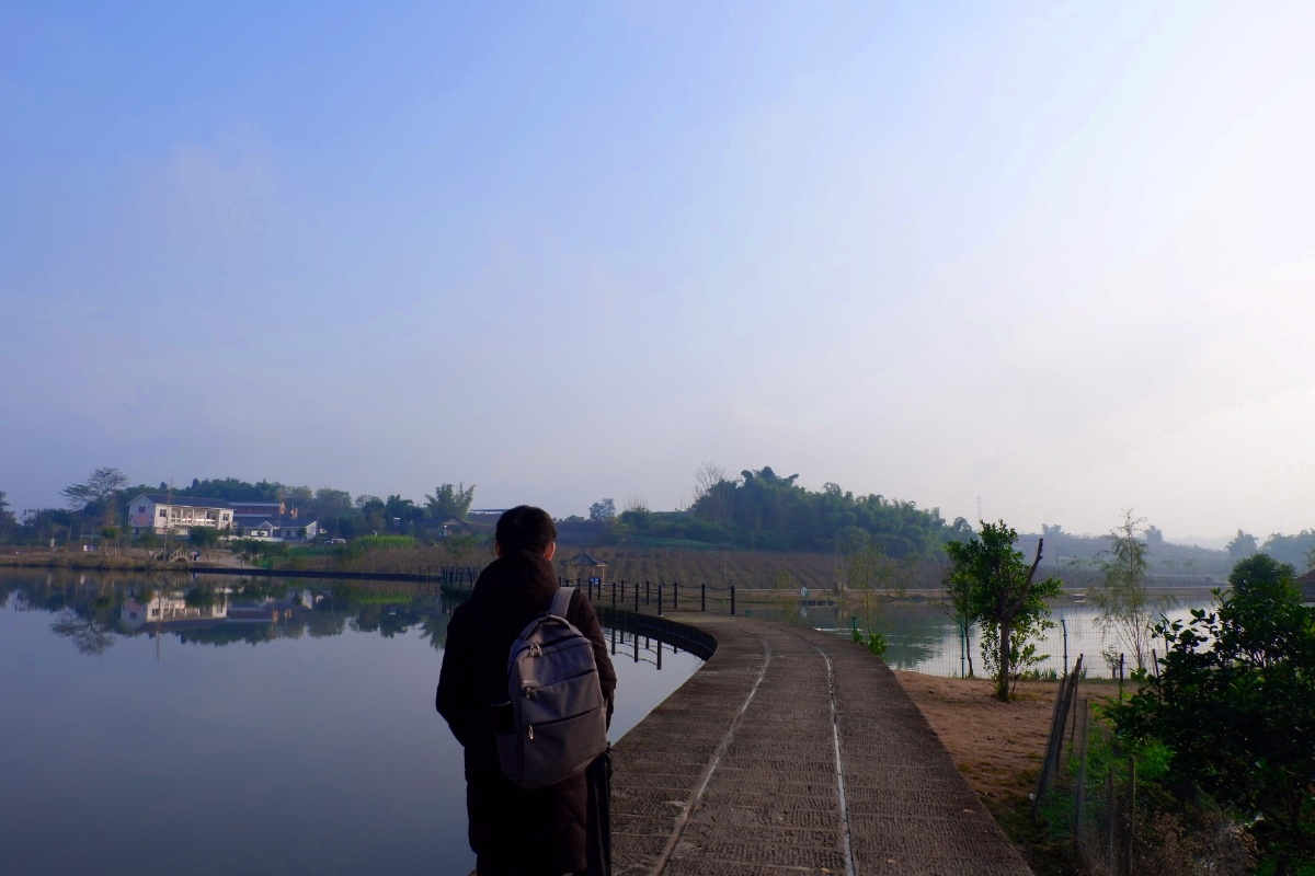 湖边路上一背包男子背影
