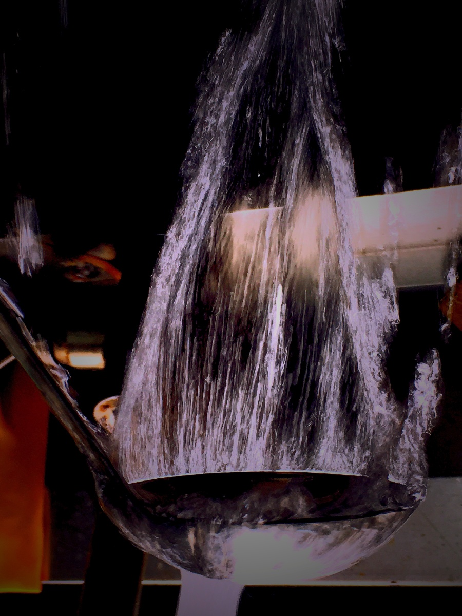 这是拿着一个勺子在水龙头上放水